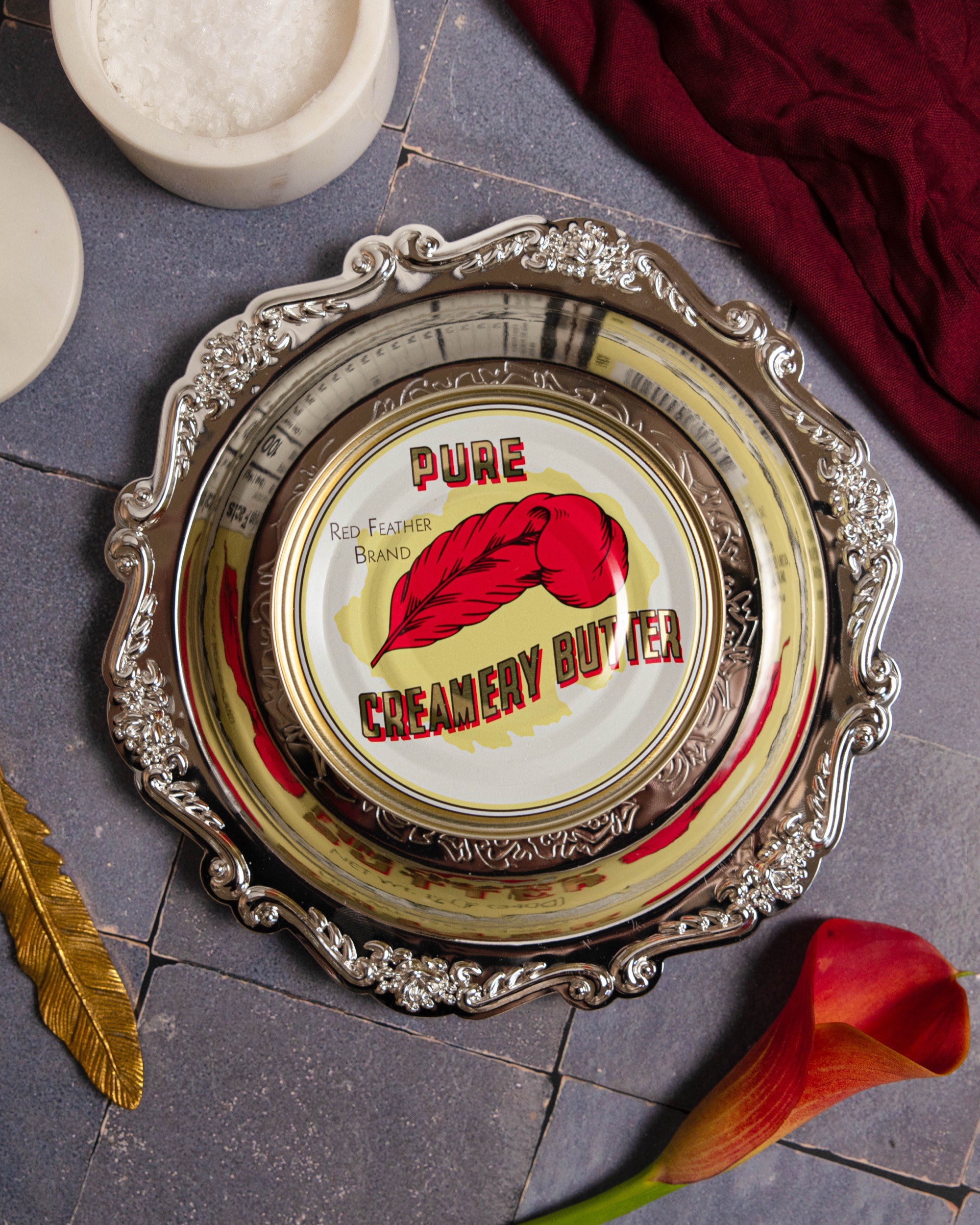 A tin of Red Feather butter on an ornate silver tray, seen from above