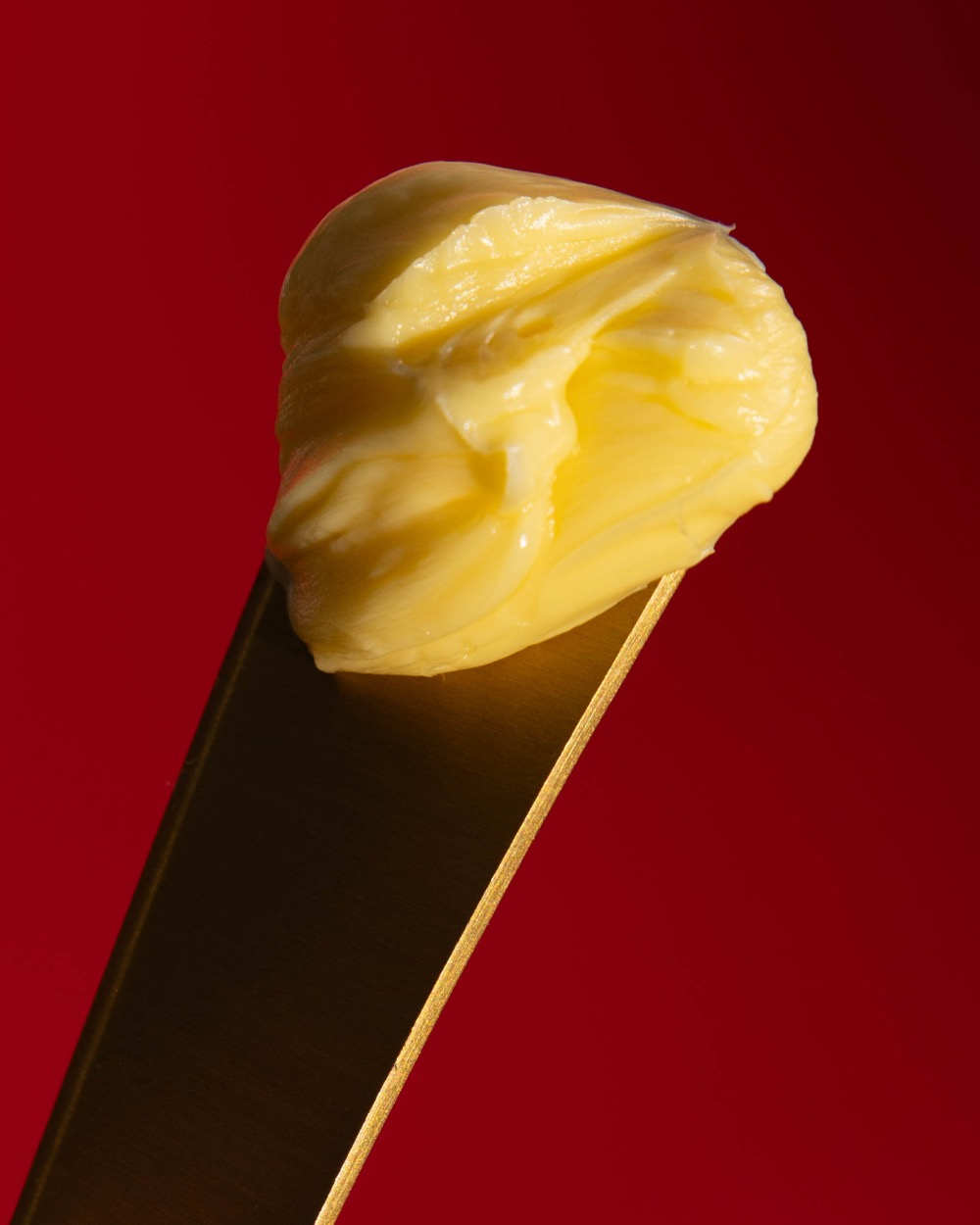 A curl of golden butter on a brass knife