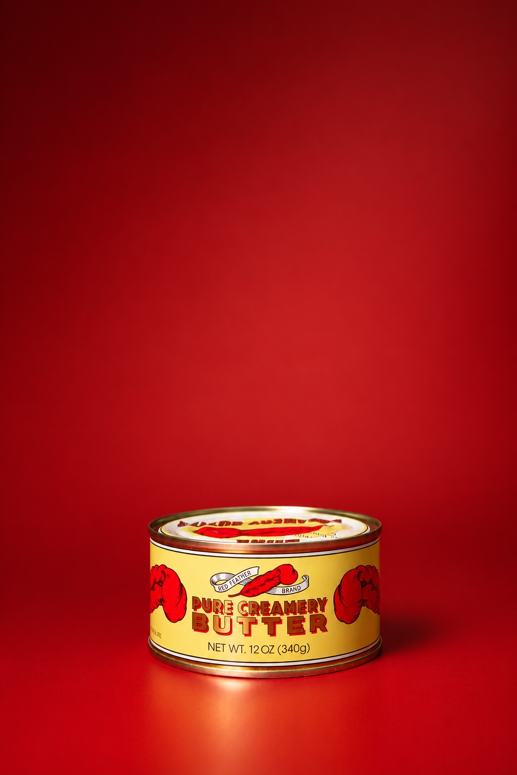 A 12 ounce tin of Red Feather butter on a deep red backdrop