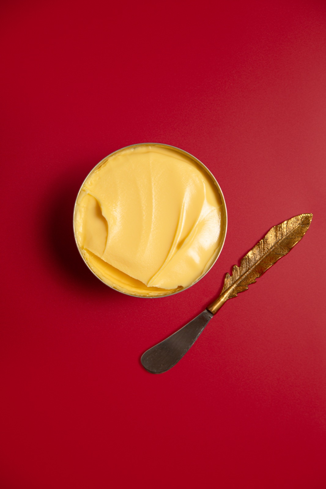 An open tin of Red Feather butter seen from above, the surface smooth and golden